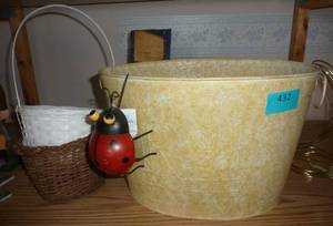 large metal basket planter with a ladybug hanging on the side, plus a couple wicker baskets