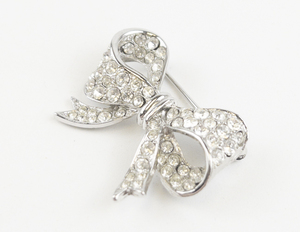 lot 114 image: Vintage Rhinestone Accented Silver Tone Base Metal Bow Brooch .