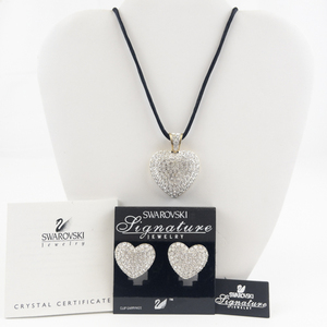 lot 165 image: Swarovski Signature Crystal Accented Heart Gold Tone Base Metal Pendant Rope Necklace & Clip-On Earrings Set With Pouch.