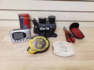 lot 64 image: 12V Air Compressor, Inner tube, 2 Tape Measures, Alarm Clock and foldable hand held cutter
