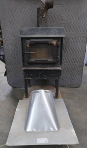 lot 65 image: BLACK CAST IRON STOVE ON STAND WITH ROOF VENT