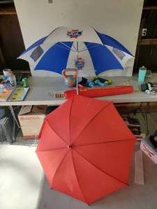lot 295 image: 2 umbrellas, Red one is hand held, Old Style is either hand heald or has in the ground Extension, along with Hand weights and more