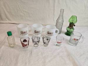 lot 327 image: Vintage Glassware and Collectibles Lot including Belview State Bank mugs, several unique shot glasses, an A&W glass mug, a small green oil lamp, and assorted vintage bottles