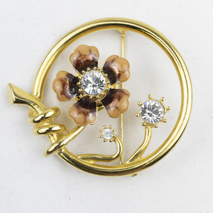 lot 287 image: Joan Rivers Enameled Flower & Rhinestone Gold Tone Base Metal Set In Circle Brooch.