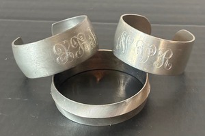lot 40 image: Two Pewter Monogrammed Bracelets and Silver Plated Bracelet