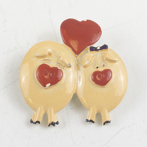 lot 202 image: Two Pig In Love Base Metal Brooch .
