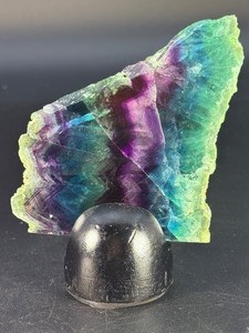lot 71 image: Rainbow Fluorite Slab is a stunning, polished slice that showcases fluorites signature bands of purple, green, blue, and soft teal hues. 5.6 oz.  0.161 kg.
