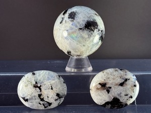 lot 78 image: Rainbow Moonstone Sphere and Palm Stones are enchanting pieces that showcase the soft, luminous glow and signature flashes of rainbow sheen unique to rainbow moonstone.&nbsp