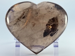lot 84 image: Large Smoky Quartz Heart with Rainbows &amp Inclusions is a striking, hand-polished crystal heart. The rich, earthy tones of smoky quartz along with natural internal inclusions that create captivating rainbows. 2 lbs 6.2 oz.  1.085 kg