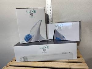 lot 37-F2025 image: Three new inbox Luxe items, compact steam iron, handheld garment steamer, and three tiered laundry cart.