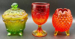 lot 22 image: Fenton Amberina Hobnail Three Footed Egg, L.E. Smith Amberina Grape & Leaf Pattern Water Glass, and Jeanette Glass Covered Candy Dish