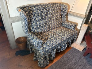 lot 250 image: Blue country print wingback settee (loveseat) with ruffled skirt.  L 57 x H 40 x W 29 Bring help to move.