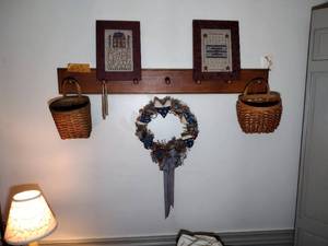 lot 303 image: Primitive style pictures, mail baskets, wax candles, and wreath wall mounted peg shelf.