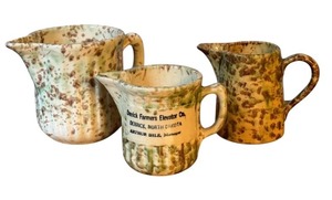 lot 36 image: Set of 3 Vintage Pottery Creamers including a Vintage Derrick Farmers Elevator Co. Advertising Pottery Creamer
