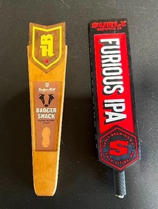 lot 97A image: Two Beer Tap handles including Badger Snack Peanut Butter Stout, from Badger Hill Brewing Co., and Surly Furious IPA, from Surly Brewing Co.