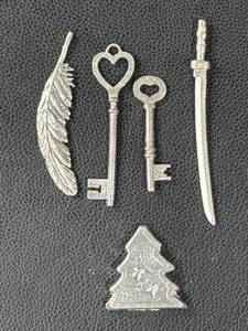 lot 184 image: 104 Grams of .999 Silver Poured Shapes Including Feather, Keys, Sword, and Christmas Tree