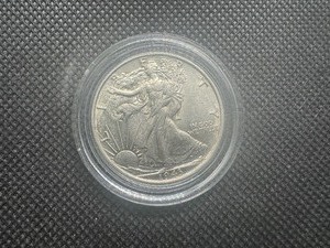 lot 21 image: 1943 AU Walking Liberty Half Dollar. Very Lightly circulated. Near full mint luster. Full mint details remain on collar, hairline, left hand and left leg.