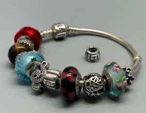 lot 111 image: Pandora Classic Sterling Silver Bracelet with 13 Assorted Silver & Glass Troll Beads