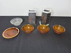 lot 238 image: Kitchenware Set with 2 Box Graters, Glass Bowl, Stoneware Plate, and 3 Amber Bowls