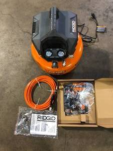 lot 27 image: RIDGID 6 Gal. 150 PSI Portable Electric Oil-Free Jobsite Pancake Air Compressor with 25 ft. Air Hose and 18GA Brad Nailer Slight Damage  Customer Returns See Pictures