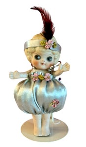 lot 12D image: LR - 5.5 Inch Vintage Porcelain Doll with Satin Outfit and Feather Headband