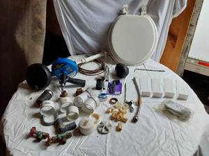 lot 277 image: Assorted Plumbing Supplies and Tools including Drill Powered Drain Auger, Toilet Seat, and Various Fittings