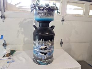 lot 20 image: Hand-Painted Winter Cabin Scene Milk Can with Faux Plant
