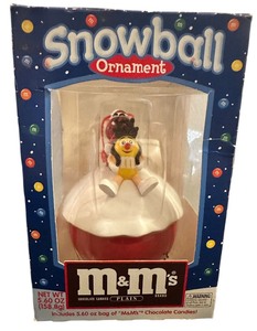 lot 188 image: Vintage M&Ms Snowball Christmas Ornament. It features the yellow M&M character in a red sleigh on a snowball base