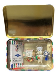 lot 456 image: Pillsbury Doughboy 50th Anniversary Bake-Off tin. The tin contains three ornaments and a mini cookbook