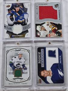 lot 84 image: Jay Bouwmeester In The Game Heroes and Prospects Patch, Ross Colton 2021-22 Upper Deck Series 2 Rookie Threads Patch, Jaden Schwartz 2018-2019 Upper Deck UD Game Jersey Patch, Hunter Shinkaruk 2015-16 Upper Deck Champs Rookie Patch