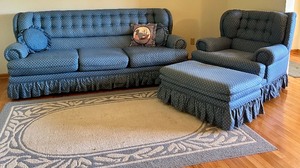 lot 81 image: Blue Upholstered Sofa, Chair, and Ottoman Set with Skirted Detailing and Area rug