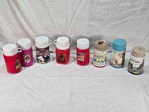 lot 15 image: Collection of Vintage Thermo Bottles Featuring ALF, Barbie, Raggedy Ann, Mr. T, Garfield, Lazer Tag, and Holly Hobbie