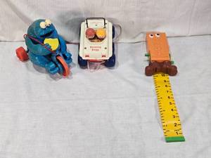 lot 31 image: Fisher-Price Vintage Toys including 1973 Bouncing Buggy, Cookie Monster Pull Toy, and Measuring Man