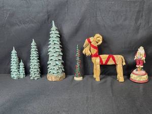 lot 185 image: Holiday Decor Collection with Carved Trees, Straw Goat, and Merry Christmas Santa Figure