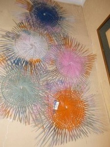 lot 235 image: This is a collection of assorted, colorful vintage string art sunburst wall sculptures, also known as sun plates.