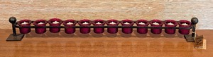 lot 163 image: LL - Jan Barboglio Long Wrought Iron Votive Candle Holder with 12 Red Glass Votive Holders