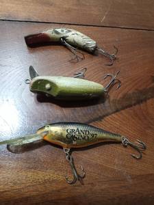 lot 65 image: Original Lazy Ike wood fishing lure. vintage Creek Chub Spoon tail fishing lure, and 1977 Commemorative Grand Casino fishing lure