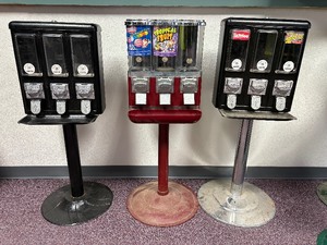 lot 86 image: 3 Pc Lot 3 Cast Metal Candy Machines, the 2 Black Machines Have Metal Stands & The Red Has Plastic - No Keys