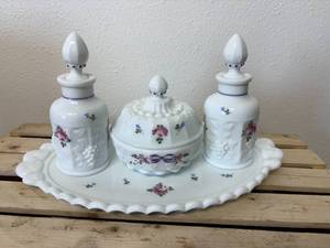 lot 20 image: This is a vintage Westmoreland milk glass dresser set in the Paneled Grape pattern, hand-painted with a Roses & Bows design. The set includes two perfume bottles with stoppers, a covered powder box, and an oval vanity tray.