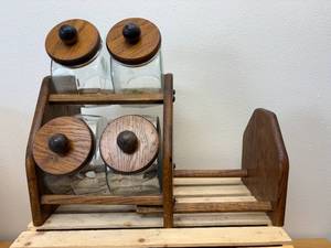 lot 24 image: Vintage general store style canister set, The item is a set of four clear glass jars with solid wooden lids and a matching wooden storage rack