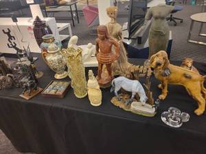 lot 141 image: A table full of decor items, animal figures, pottery, glassware, bookends, candle holders, dolls etc.