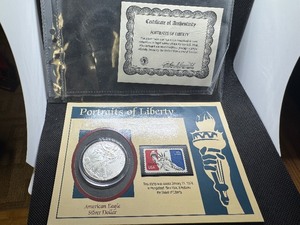lot 49 image: Portraits of Liberty Card with COA 1998 Silver Dollar and 1974 Statue of Liberty Stamp