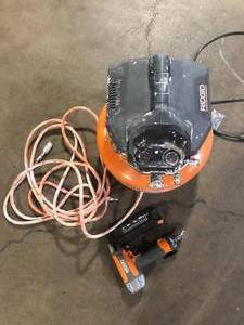 lot 12 image: RIDGID 6 Gal. 150 PSI Portable Electric Oil-Free Jobsite Pancake Air Compressor with 25 ft. Air Hose and 18GA Brad Nailer Good Used Customer Returns See Pictures
