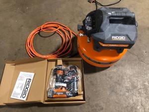 lot 140-1 image: RIDGID 6 Gal. 150 PSI Portable Electric Oil-Free Jobsite Pancake Air Compressor with 25 ft. Air Hose and 18GA Brad Nailer Customer Returns See Pictures