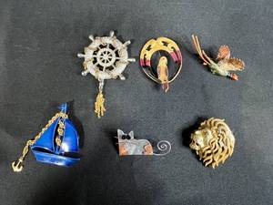 lot 209 image: Collection of Costume Brooches Including Cat, Lion, Bird, Sailboat, Nautical Wheel, and Abstract Designs
