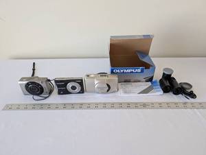lot 97 image: Lot of 3 Digital Cameras and Film Accessories - Canon, Olympus FE, Olympus Stylus Zoom