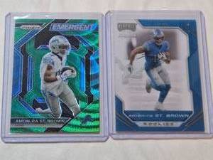 lot 213 image: Lot of 2 Amon-Ra St. Brown Football Cards Featuring Prizm Emergent Refractor and Chronicles Playoff Momentum Rookie Cards