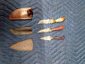 lot 74 image: Stag antler handle Damascus steel blade knife with sheath, Red toned wood handle with forged Damascus steel blade and sheath,and a wood handle Damascus steel blade dagger with sheath