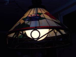 lot 30 image: This is a Tiffany-style stained glass hanging pendant light fixture with a floral motif and a wrought iron frame