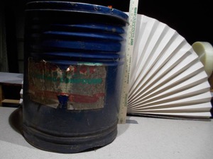 lot 76 image: The can is a large, blue metal drum with a heavily worn paper label